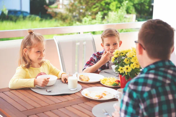 幸せな若い家族が家の大きなテラスで朝食中に楽しんでいます — ストック写真