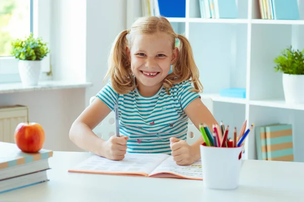 教室で本を持つテーブルで面白い小さな学校の女の子の肖像画 — ストック写真