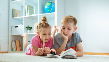 Katta evde kitap okurken iki mutlu çocuk portresi
