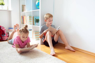 İki mutlu çocuk yerde okul Kütüphanesi'nde kitap okuma