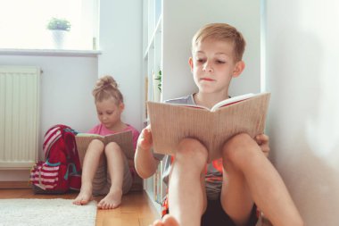 İki mutlu çocuk yerde okul Kütüphanesi'nde kitap okuma