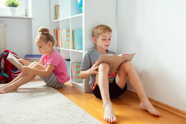 两个快乐的孩子在学校图书馆的地板上看书 — 图库照片