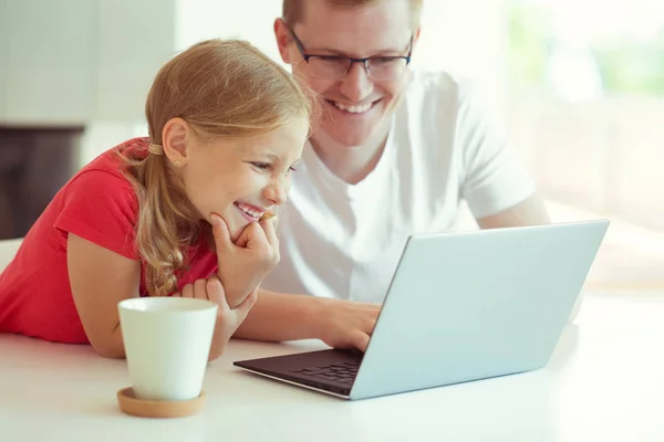 愉快的年轻的父亲有乐趣与他漂亮的小女儿在工作与笔记本电脑在现代家庭 — 图库照片