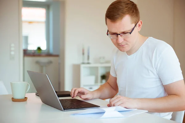 Hombre joven que trabaja con el ordenador portátil en casa — Foto de Stock