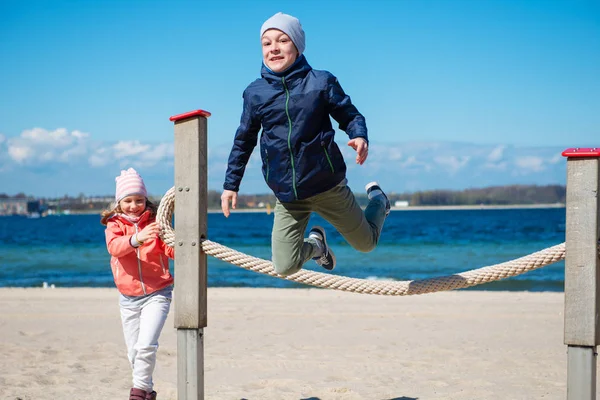 Crianças felizes brincando no playground em uma praia — Fotografia de Stock