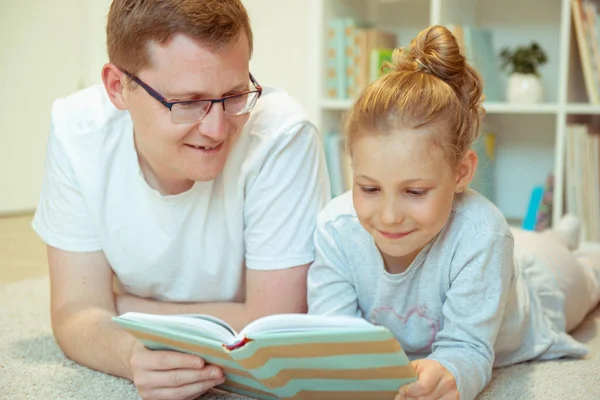 Genç, mutlu baba evde tatlı kızıyla kitap okuyor. — Stok fotoğraf
