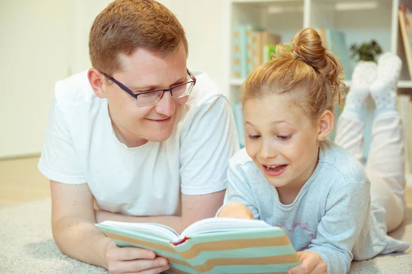 Joven padre feliz lectura libro con linda hija en casa — Foto de Stock