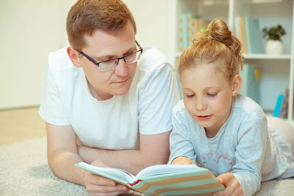 Genç, mutlu baba evde tatlı kızıyla kitap okuyor. — Stok fotoğraf