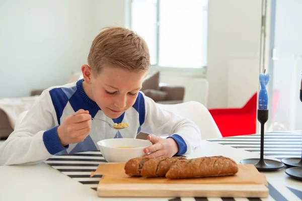 Guapo adolescente comiendo sopa y pan de grano entero en li brillante —  Fotos de Stock