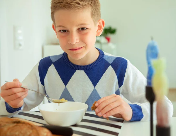 Gutaussehender Teenager isst Suppe und Vollkornbrot in hellem Licht — Stockfoto