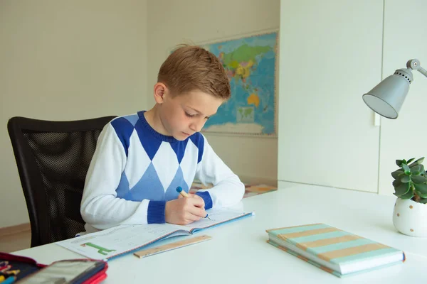 Rapaz inteligente faz trabalhos de casa no seu quarto — Fotografia de Stock