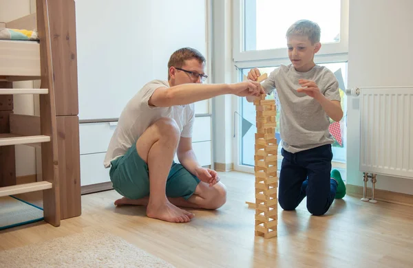 Mladý šťastný otec hrát se svým synem s dřevěnými bloky na th — Stock fotografie