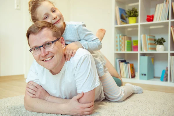 Joven padre feliz lectura libro con linda hija en casa —  Fotos de Stock