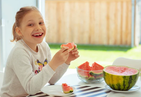 Lycklig söt liten flicka äter söt vattenmelon i ljust boende — Stockfoto