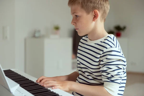 Мальчик-подросток обучается игре на электронном фортепиано дома — стоковое фото