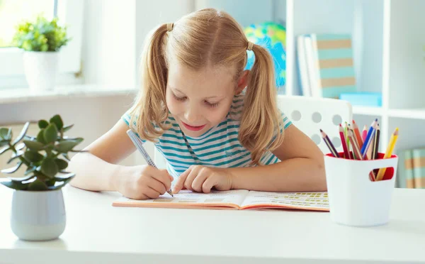 Portret van school meisje in de klas schrijven aan de tafel — Stockfoto