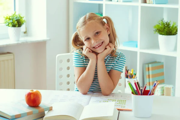 Retrato de menina da escola bonito sentado na mesa branca na luz — Fotografia de Stock