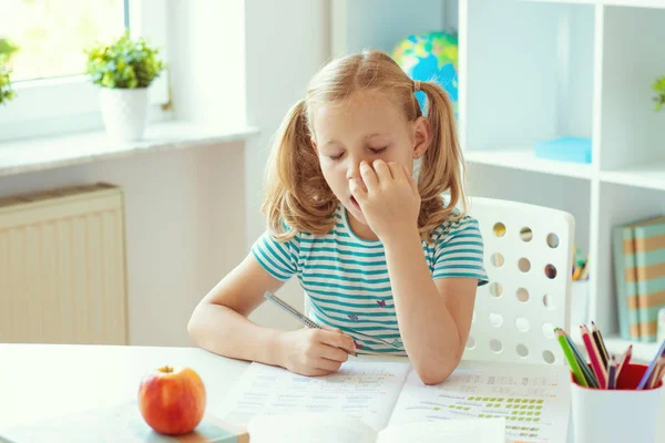 Portret zmęczonej małej uczennicy przy stole w klasie — Zdjęcie stockowe