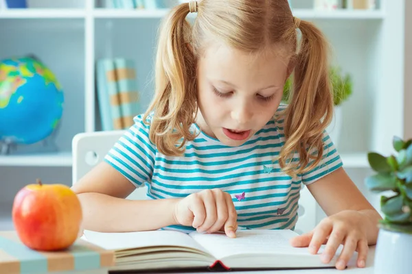 Portrét roztomilou holčičce, která si přečetla knížku u stolu v classro — Stock fotografie
