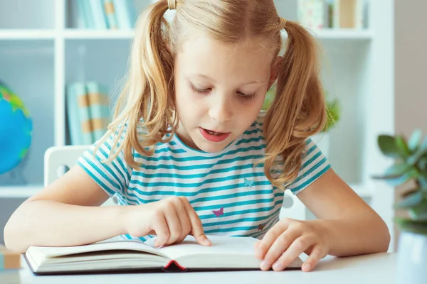 Retrato de uma menina bonito ler livro na mesa em classro — Fotografia de Stock