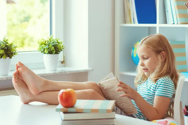 Porträtt av rolig liten skol flicka avkopplande läser bok på — Stockfoto