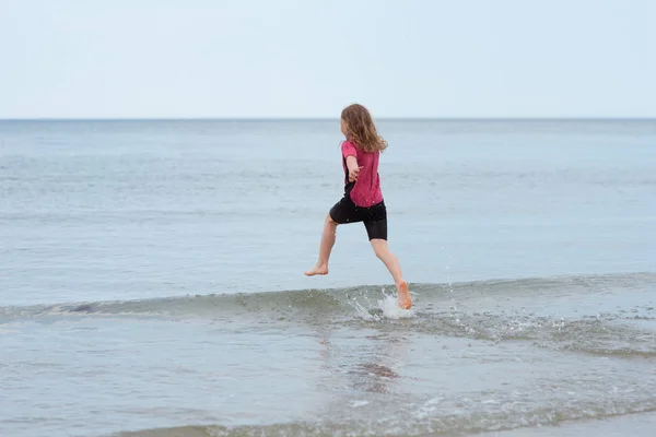Щаслива маленька дівчинка бігає в морі і грає з хвилями — стокове фото