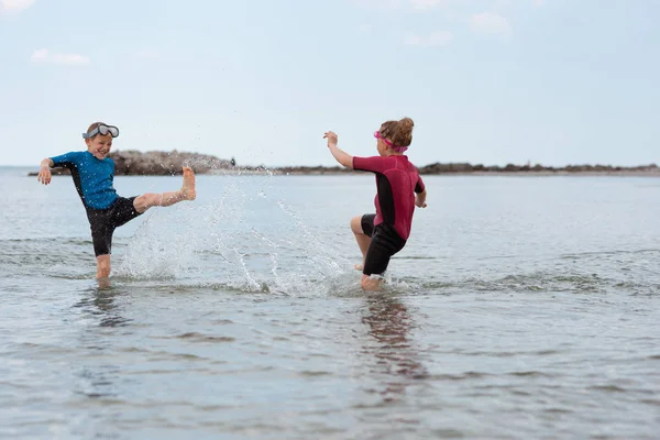Two happy siblings children in neoprene swimingsuit  playin and — Stock Photo, Image