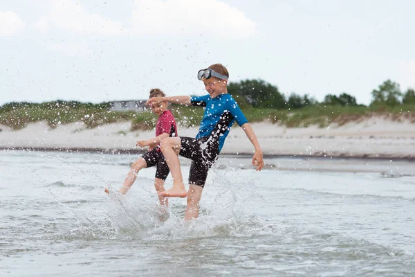 Two happy siblings children in neoprene swimingsuit  playin and — Stock Photo, Image