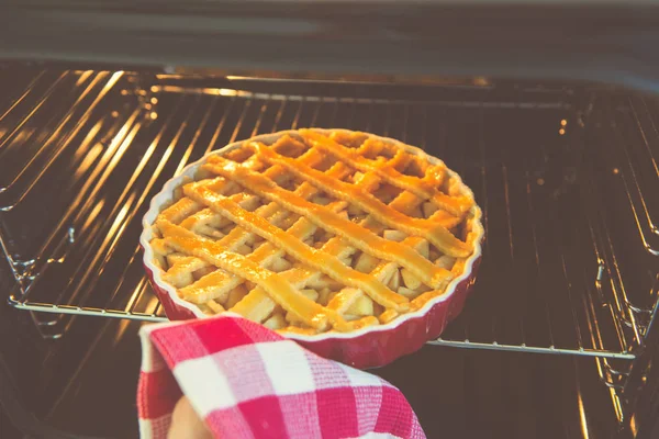 Fresh baked golden apple pie in red dish in oven at kitchen — Stock Photo, Image
