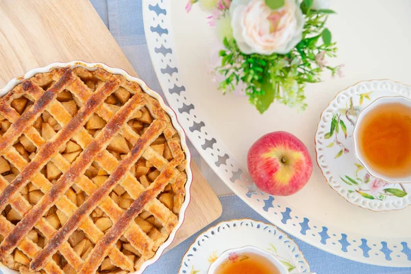 Fresh baked apple pie, cup of tea and flowers on a table — Stock Photo, Image