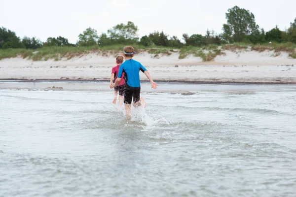 Two happy siblings children in neoprene swimingsuit  playin and — Stock Photo, Image