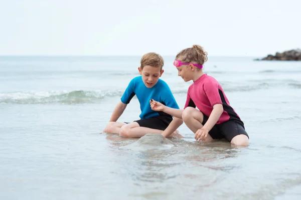 Dvě šťastné sourozence v neopradných plavcích si hrají s s — Stock fotografie