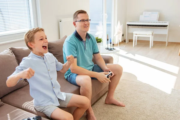 Feliz padre joven y su hijo jugando juegos de ordenador con estafa —  Fotos de Stock
