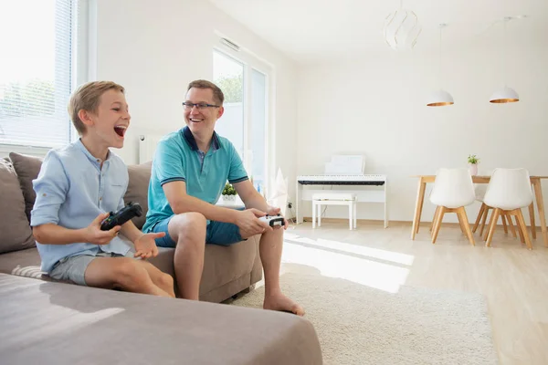 행복한 젊은 아버지와 그의 아들이 컴퓨터 게임을하고 있습니다. — 스톡 사진