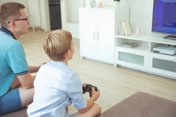 Glücklicher junger Vater und sein Sohn spielen Computerspiele mit Betrügern — Stockfoto