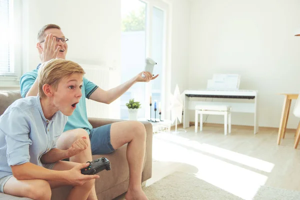 Glücklicher junger Vater und sein Sohn spielen Computerspiele mit Betrügern — Stockfoto