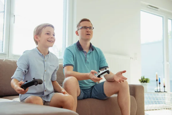 Glücklicher junger Vater und sein Sohn spielen Computerspiele mit Betrügern — Stockfoto