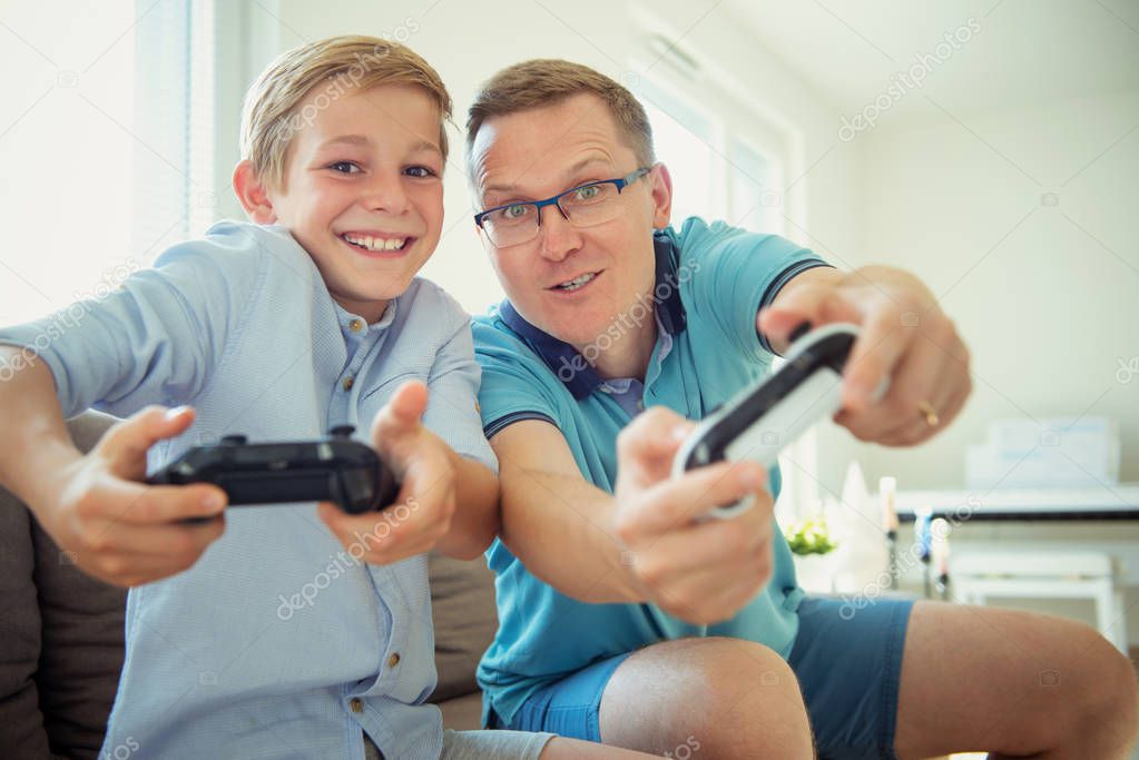 Happy young father and  his son playing computer games  with con
