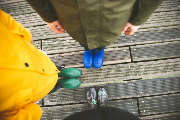 Family of three standing on woode pier in high rubber boots — Stock Photo, Image