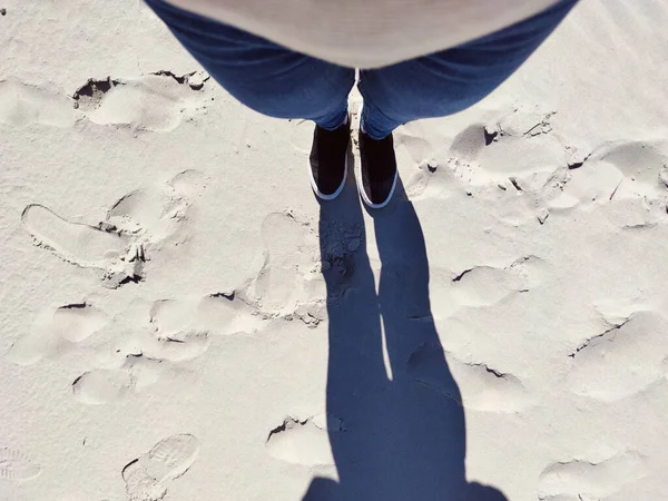 白い砂の上にジーンズやスニーカーで立って足の写真 上からの眺め — ストック写真