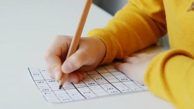 Evde hobi olarak çocukların ellerinin sudoku bulmacalarını çözerken çekilmiş bir video.