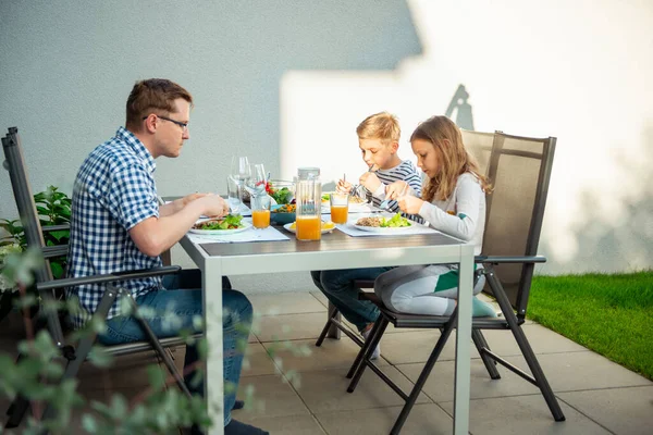 Happy family eating healthy dinner together on terrace at home