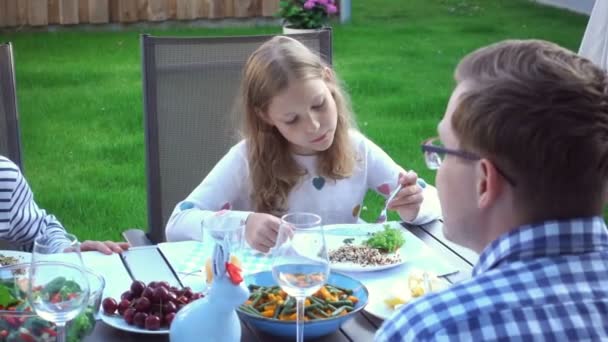 2人の幸せな10代の子供は 居心地の良い裏庭のテラスで両親の健康的な夕食と楽しく話して食べる — ストック動画