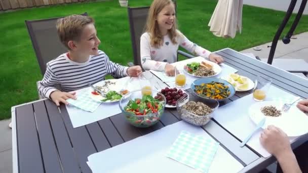 幸せな家族のビデオ彼らの美しい裏庭でテラスで健康的なディナーを食べる — ストック動画