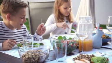 Mutlu bir ailenin terasta sağlıklı yemek yediği bir video.
