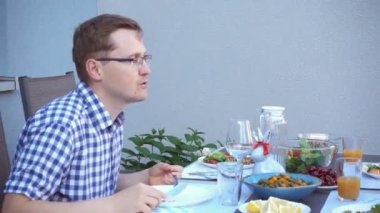 İki mutlu genç çocuk, aileleriyle sohbet edip yemek yiyorlar. Sıcak arka bahçenin terasında sağlıklı bir akşam yemeği yiyorlar.