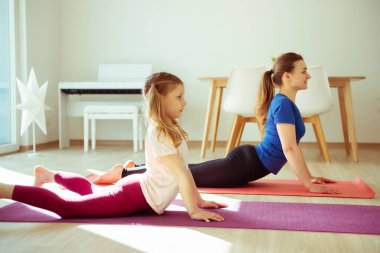 Sevimli genç kızıyla evde yoga yapan güzel bir kadın. 