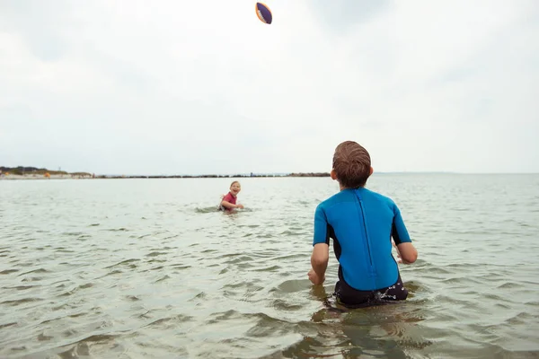 Zwei Glückliche Geschwisterkinder Spielen Und Springen Mit Ball Wasser Neoprenanzügen — Stockfoto