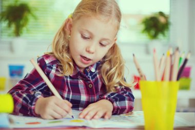 Sarı elbiseli güzel kızın portresi masada ders çalışıyor.