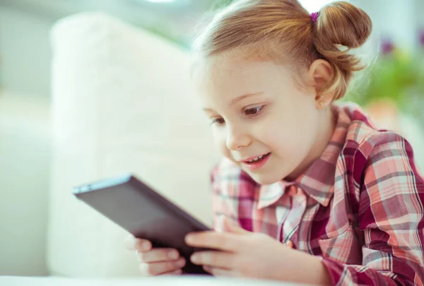 可爱的小女孩躺在沙发上的肖像 带平板电脑的数字式家庭教育 — 图库照片
